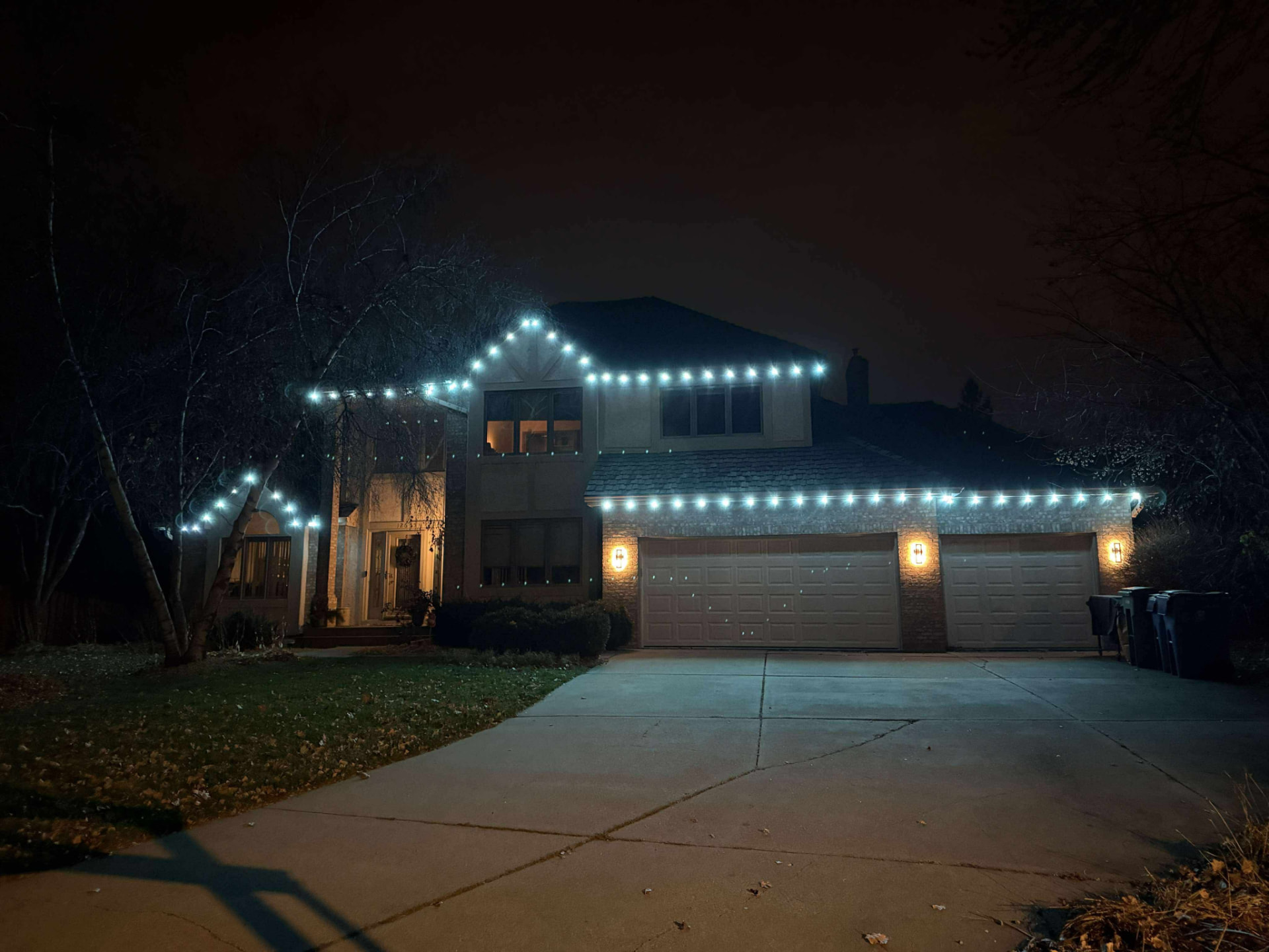 Full home wrap of cool white permanent LED lighting on a two-story home at night