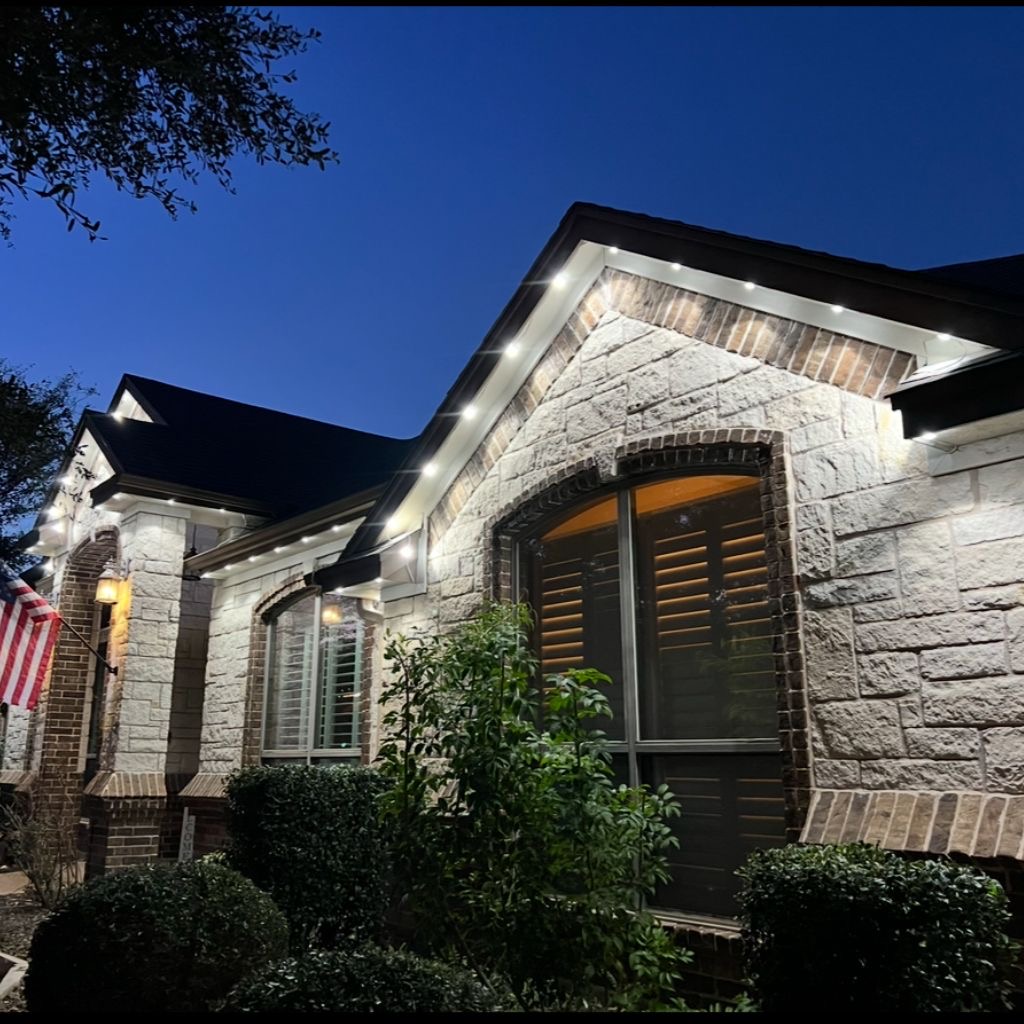 Stone home with crisp white permanent LED roofline lighting at blue hour