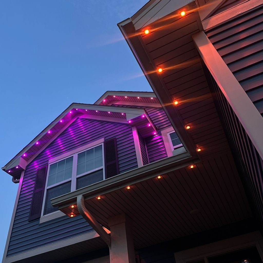 Close-up of permanent LED lights under a roofline glowing orange and purple at dusk