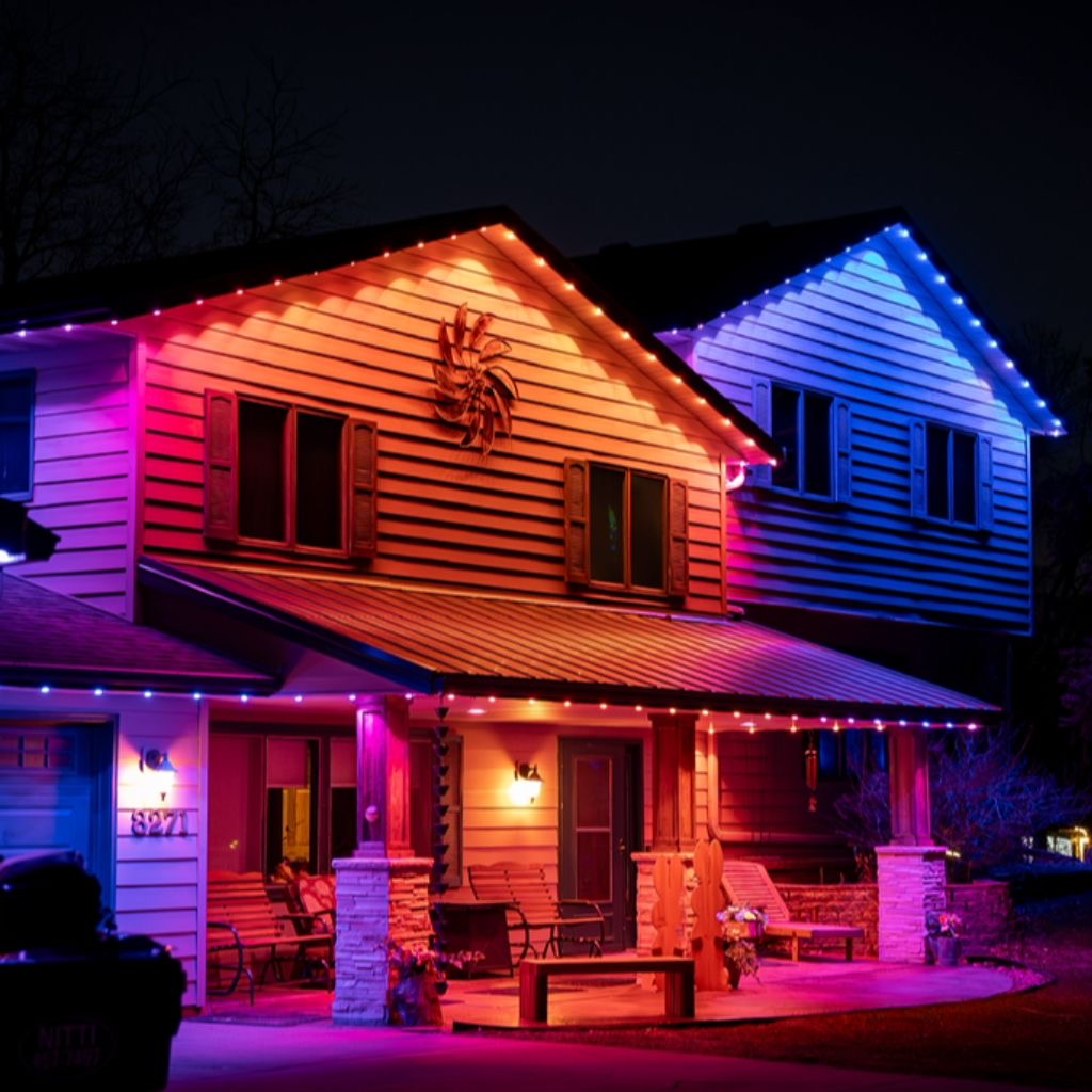 Craftsman home with multicolor permanent LED roofline and porch lighting at night